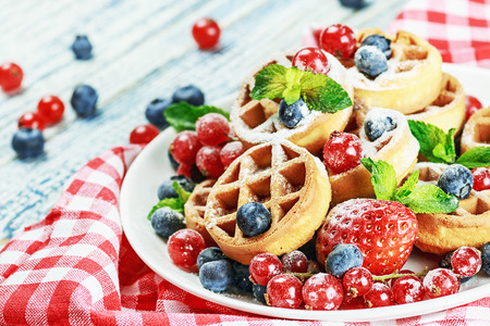 Waffles with fresh berries on the tabla. Focus on berries in the foreground. Shallow depth of fieldの写真素材