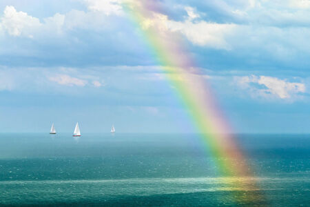 beautiful landscape with a rainbow after the rain and sailboats.focus on the waves in front of the...