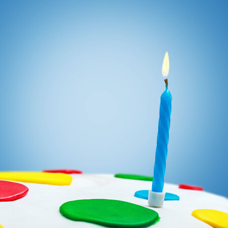 Lighted candles on a birthday cake on a blue backgroundの写真素材