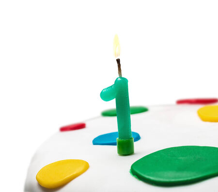 Burning candle with the number one on a birthday cakeの写真素材