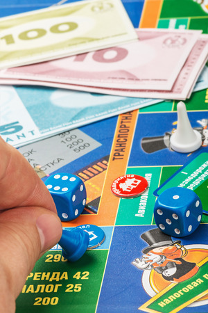 Moscow, Russia - September 11, 2014: Monopoly game on the table. Monopoly game in Russian, a board game in the genre of economic strategy for two or more people. Focus on the counter in his handのeditorial素材