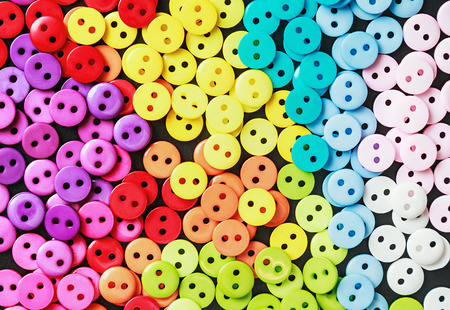 Multi colored buttons on a black background. Focus on the bud, shallow depth