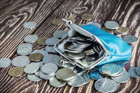 Purse with money on old rustic wooden table. Focus on the coins in the purse