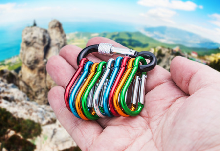 colorful carabiner climbing in hand on a background of mountains. Focus on handの写真素材