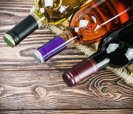 bottles of wine in a basket on a wooden tableの写真素材