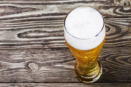 glass of fresh lager beer on a wooden tableの写真素材