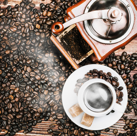 cup of warm coffee and coffee grinder on a wooden tableの写真素材
