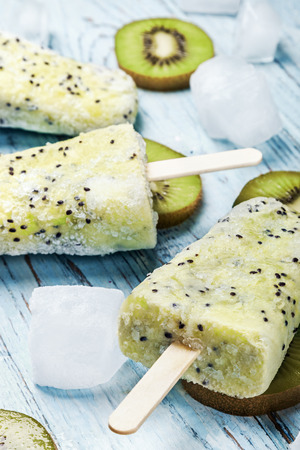 Homemade popsicles with kiwi and mint on a wooden tableの写真素材