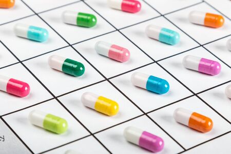 pills are of different color on a light background. Focus on a green pillの写真素材