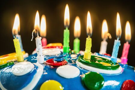 lighted candles on a birthday cake. focus on white candleの写真素材