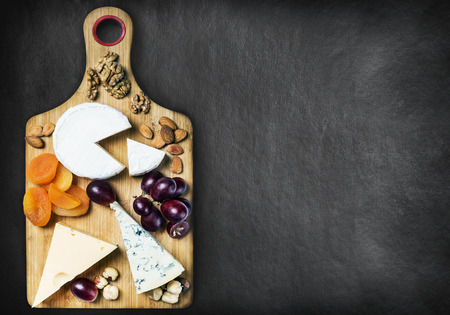 assorted cheeses, nuts and dried fruits on a black backgroundの写真素材