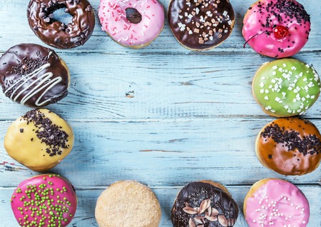Glazed donuts with different fillings on a blue wooden tableの写真素材