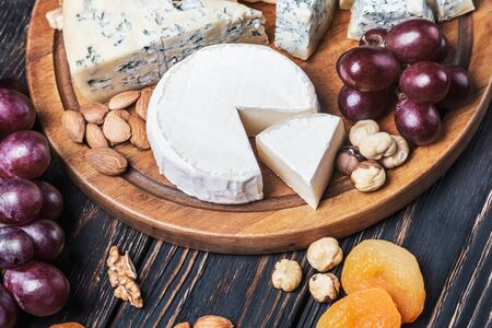 Assortment of cheese with fruits and grapes on a wooden tableの写真素材