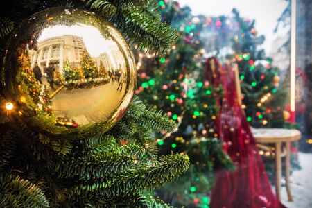 Christmas shiny ball on the Christmas tree at the fair, crowd of people reflected in mirror. Concept christmas and new year holidaysの写真素材