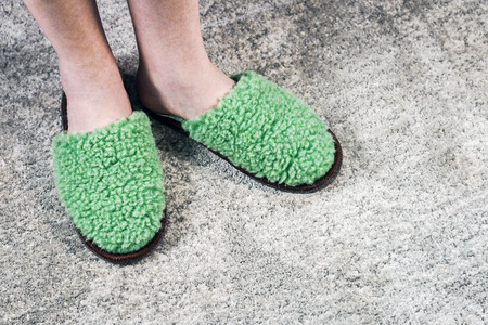 feet in green soft Slippers on the carpet in the room