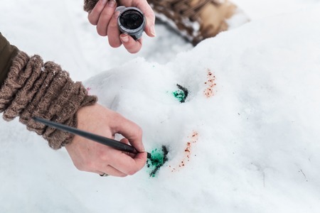 hands paint on the face of the girl sculpted from the snowの写真素材
