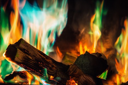 multi-colored flame of fire burns in the fireplace with firewood