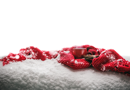 red Cup with hot drink stands wrapped with warm scarf on snow isolated on white backgroundの写真素材