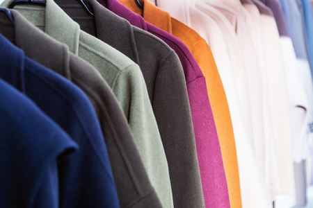 coats of different colors hang on a hanger in the storeの写真素材