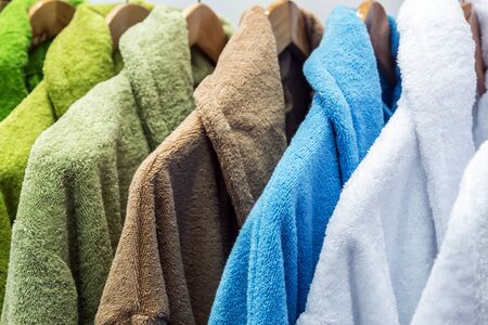 bathrobes of different colors hang on a hanger in the storeの写真素材