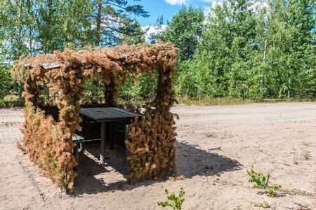 military hut of boards and branches of trees on the ground. Field shelter for military exercisesの写真素材