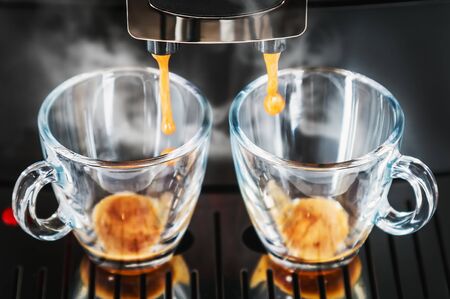 coffee beans are prepared in the coffee machine and poured into glass cups for 2 personsの写真素材