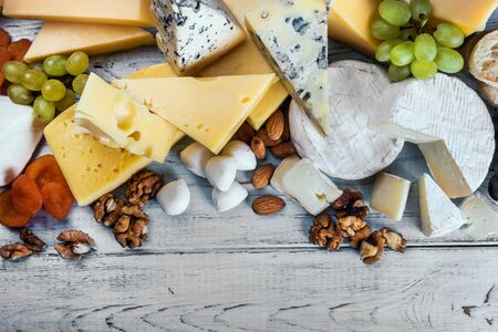 assorted different types of cheeses with fruits, nuts, dried fruits on the tableの写真素材