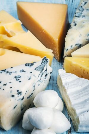 different varieties of cheese on a wooden table. Roquefort, Maasdam, emental, Gouda, Parmesan, mozzarella and other cheesesの写真素材