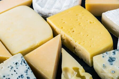 assorted cheeses, soft, hard, rennet and brine on a black tableの写真素材