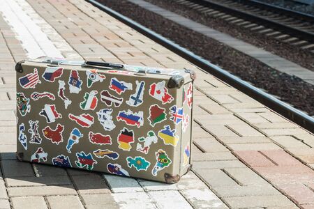 tourist suitcase with stickers of countries of the world and continents on the station platformの写真素材