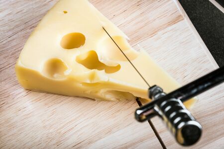 Maasdam cheese is cut on a special Board for cutting cheeseの写真素材