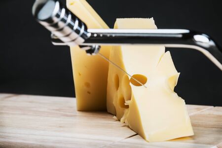 Maasdam cheese is cut on a special Board for cutting cheeseの写真素材