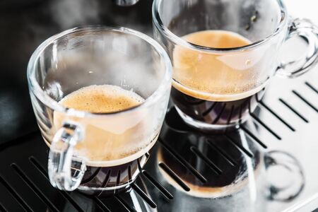 two cups of freshly brewed coffee in the coffee machineの写真素材