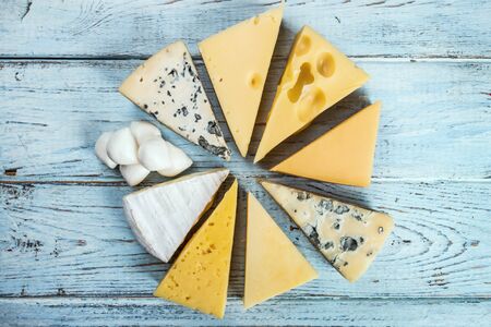 different varieties of cheese, hard, brine, soft and with mold on the tableの写真素材