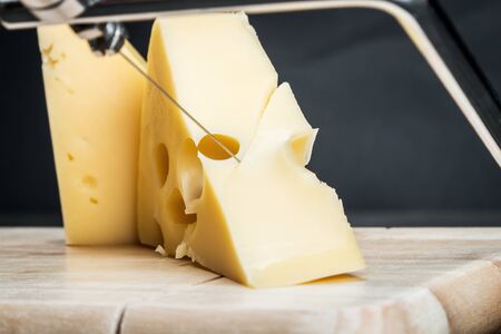 Maasdam cheese is cut on a special Board for cutting cheeseの写真素材
