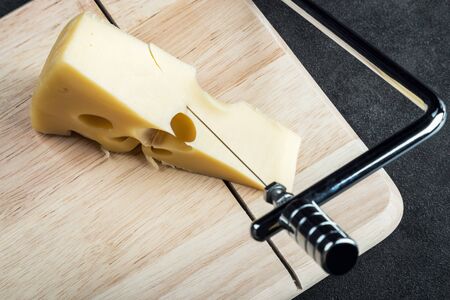 Maasdam cheese is cut on a special Board for cutting cheeseの写真素材