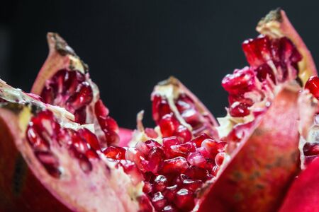 ripe pomegranate fruit with bright maroon grains. Black color backgroundの写真素材
