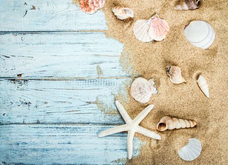 sea shells and starfish on a blue wooden background and sand. The concept of summer vacationの写真素材