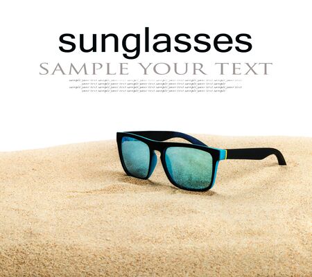 sunglasses with blue glasses on the sand in the desert isolated on a white background. Text deleteの写真素材
