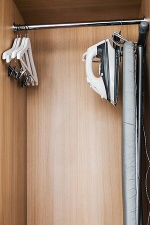wardrobe with wooden hangers without clothes and built-in Ironing stationの写真素材