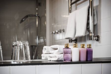 Mini bottles of cosmetics and towels on the table in the hotel room. Shampoo, body cream, conditioner and shower gelの写真素材