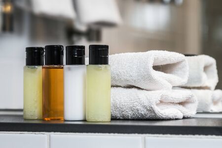 Mini bottles of cosmetics and towels on the table in the hotel room. Shampoo, body cream, conditioner and shower gelの写真素材
