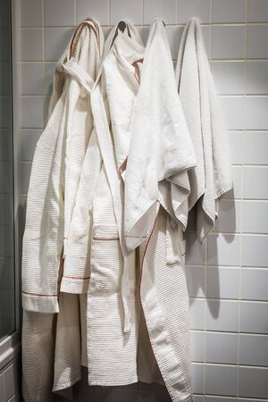 bathrobes and towels are hung on a hanger in the hotel's bathroomの写真素材