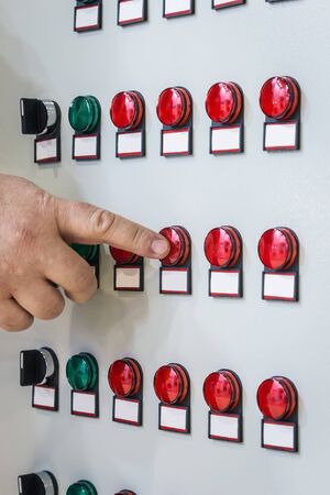 hand presses a button on the Control panel with many roundbuttons of industrial equipmentの写真素材