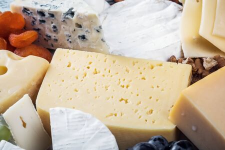 different types and varieties of cheese with grapes, nuts and dried apricotsの写真素材