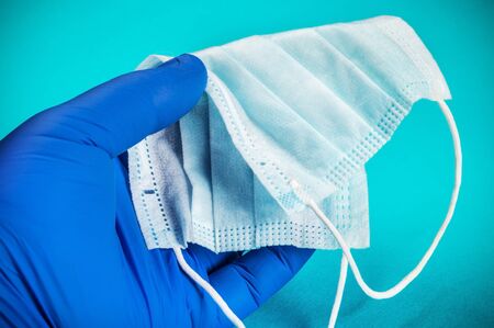 personal protective equipment against viruses and infection. A rubber-gloved hand holds a disposable face mask. Protection from covid-19 coronavirusの写真素材