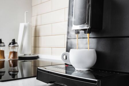 hot coffee from the coffee machine is poured into a white porcelain Cupの写真素材