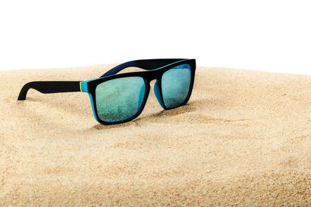 sunglasses with blue glasses on the sand in the desert isolated on a white backgroundの写真素材