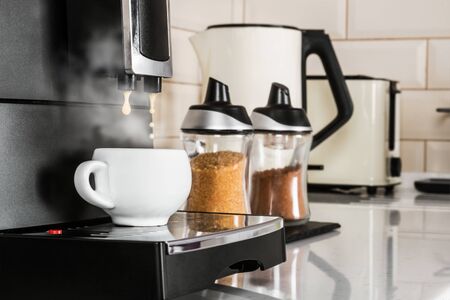 hot coffee from the coffee machine is poured into a white porcelain Cupの写真素材