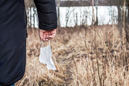 protective face mask in the hand of a tourist or traveler. Concept on the theme of freedom in the forest, in nature from infection from disease and infection from the virusの写真素材